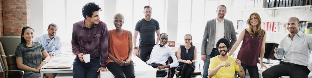 Group of 11 diverse employees smiling at the camera in an office setting