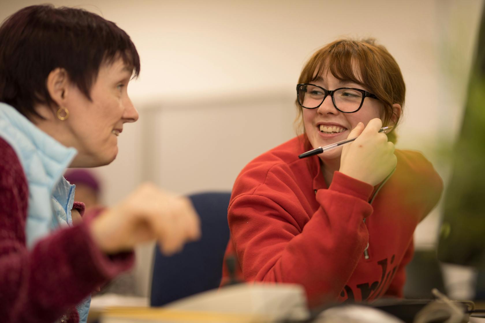 Lecturer and student chatting over their work.