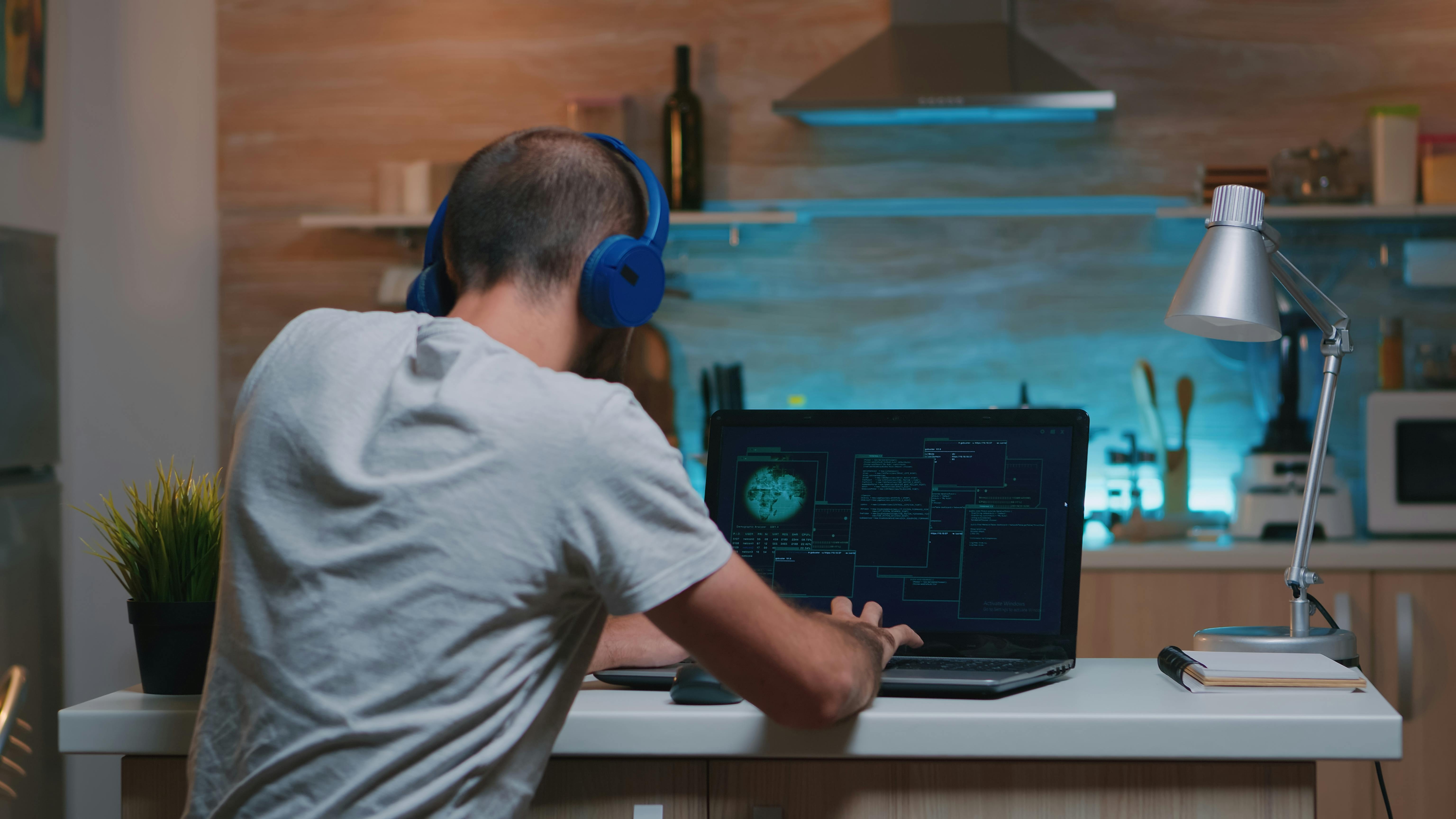 a male student is self-learning how to code on computer wearing headphones