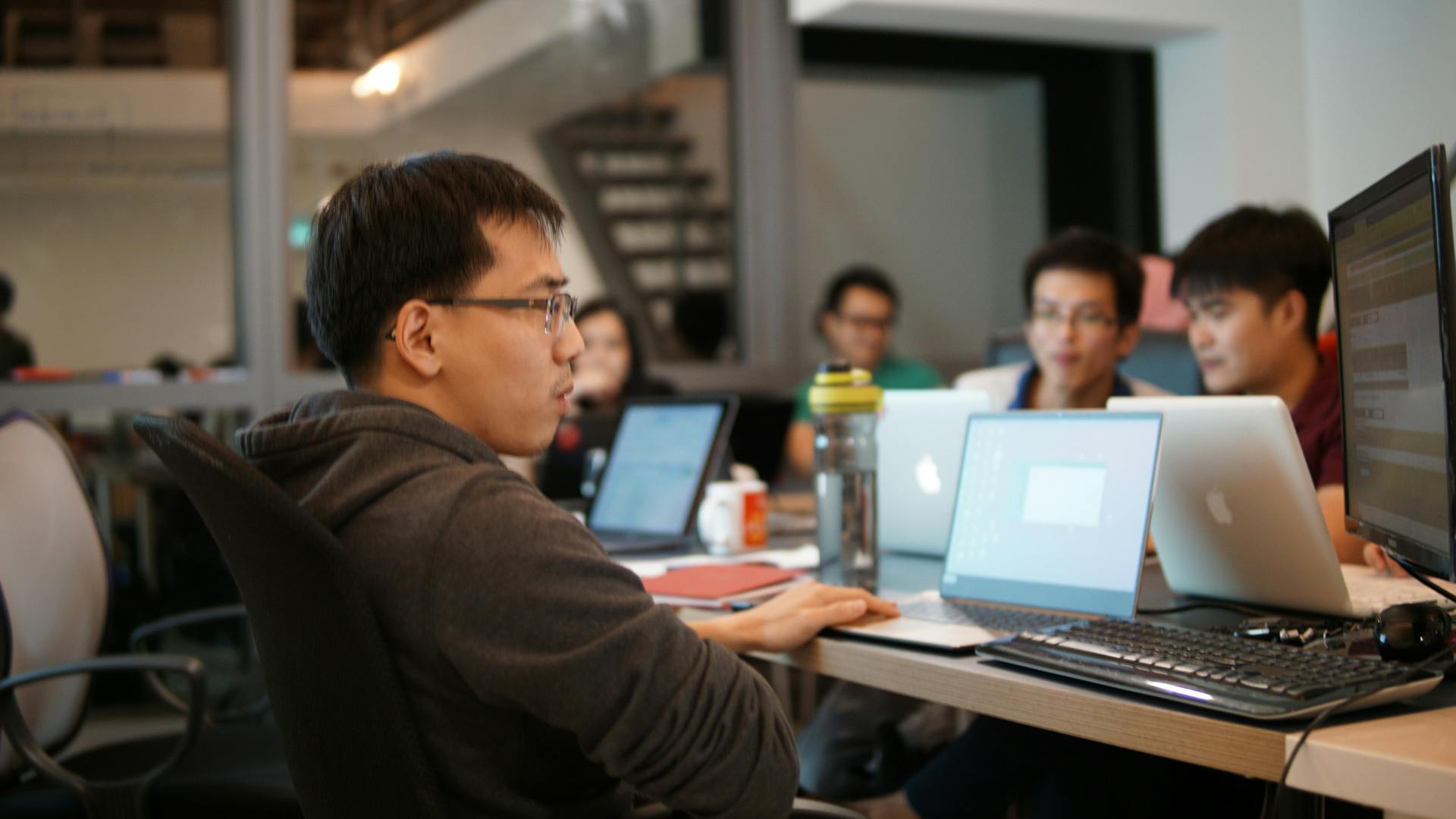 a group of Asian guys, working on their computer in the classroom, learning to code