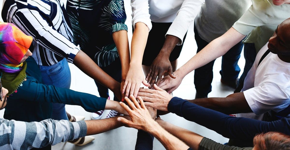 a diverse group of people joining hands