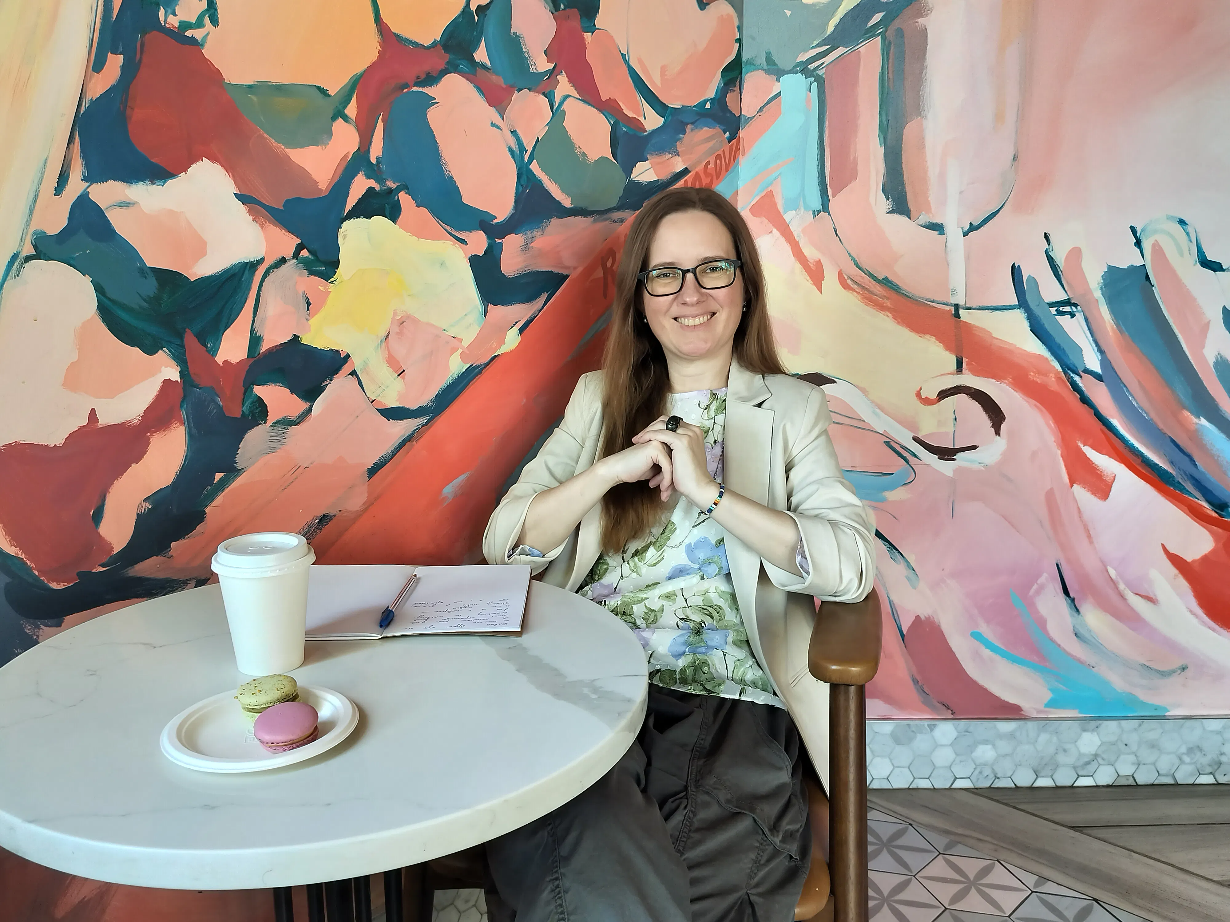 woman sitting at a table with writing materials, smiling