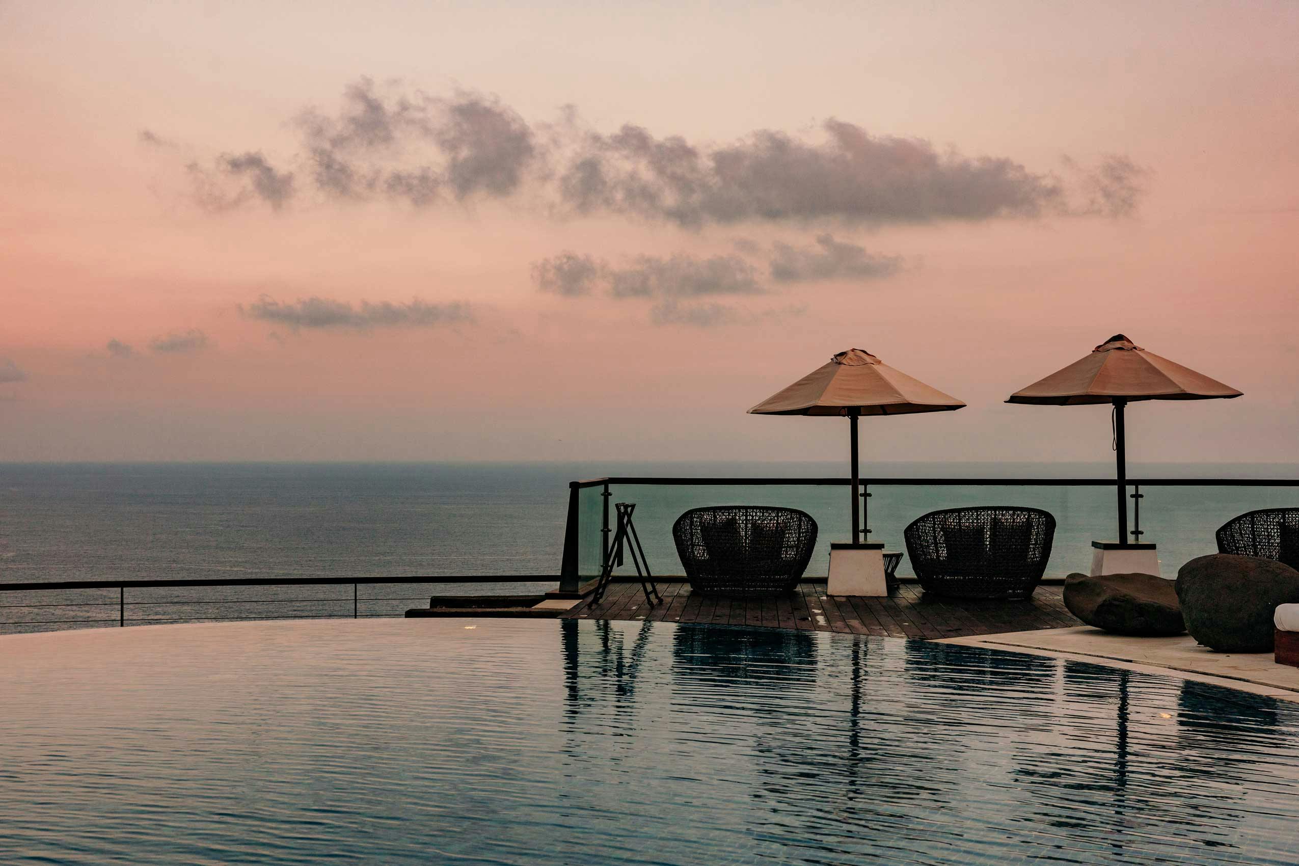 Sunset by an Infinity pool on the side of the cliff in Uluwatu Bali