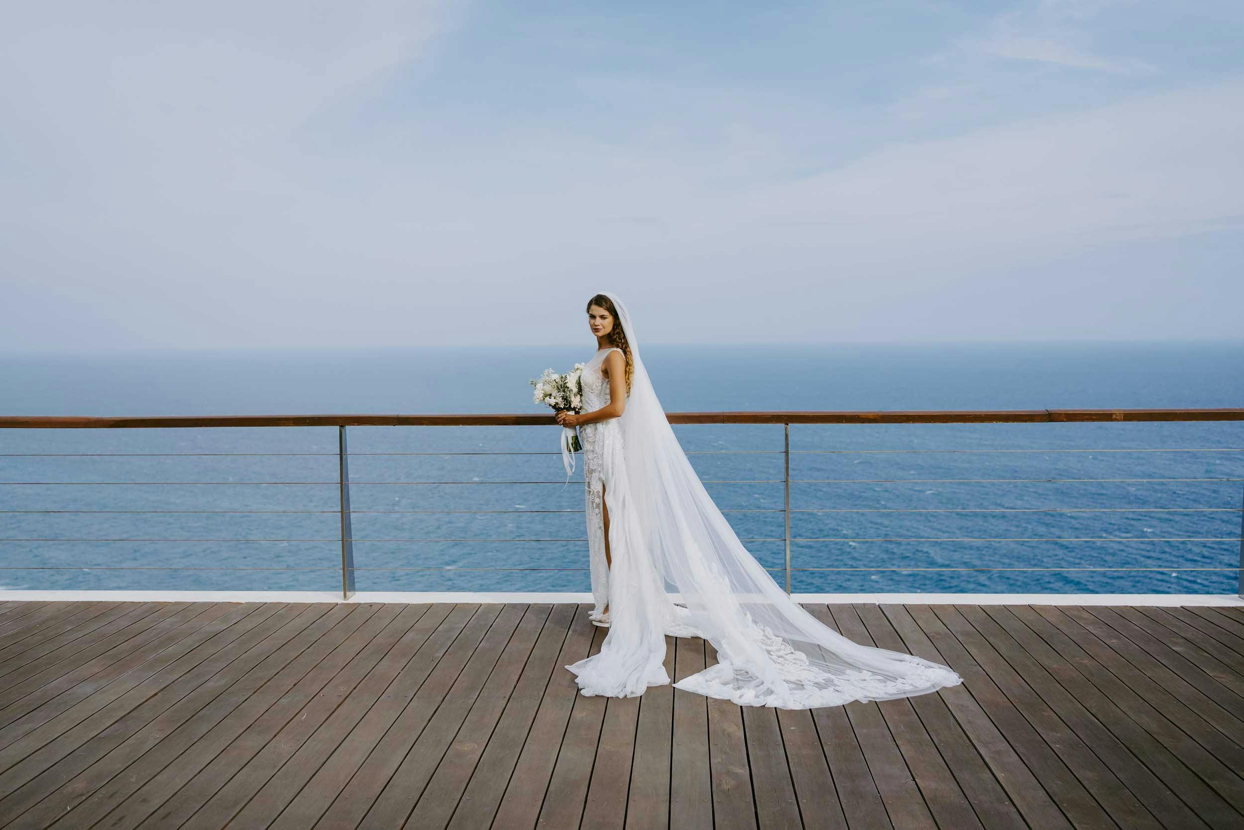 Beautiful bride standing on the cliff with endless ocean views