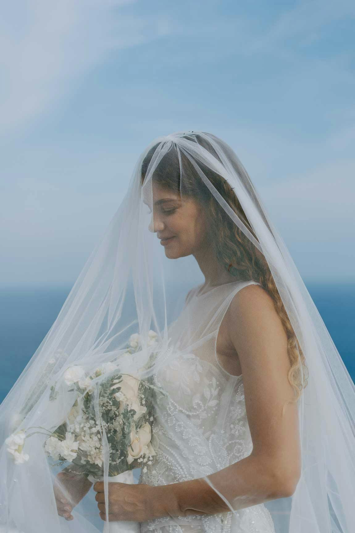 Beautiful bride standing on the cliff with endless ocean views