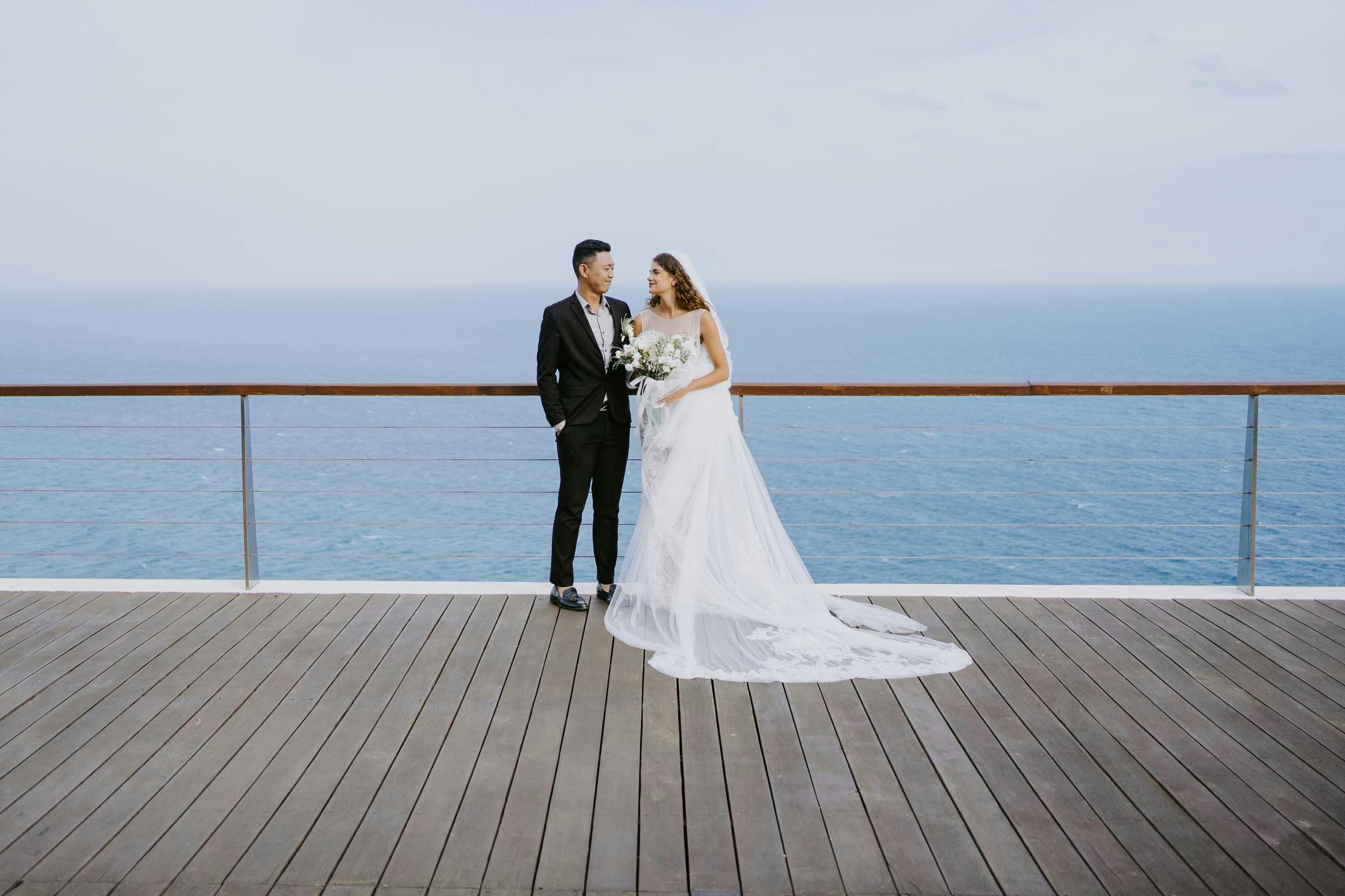 bride and groom standing on the cliff with endless ocean views