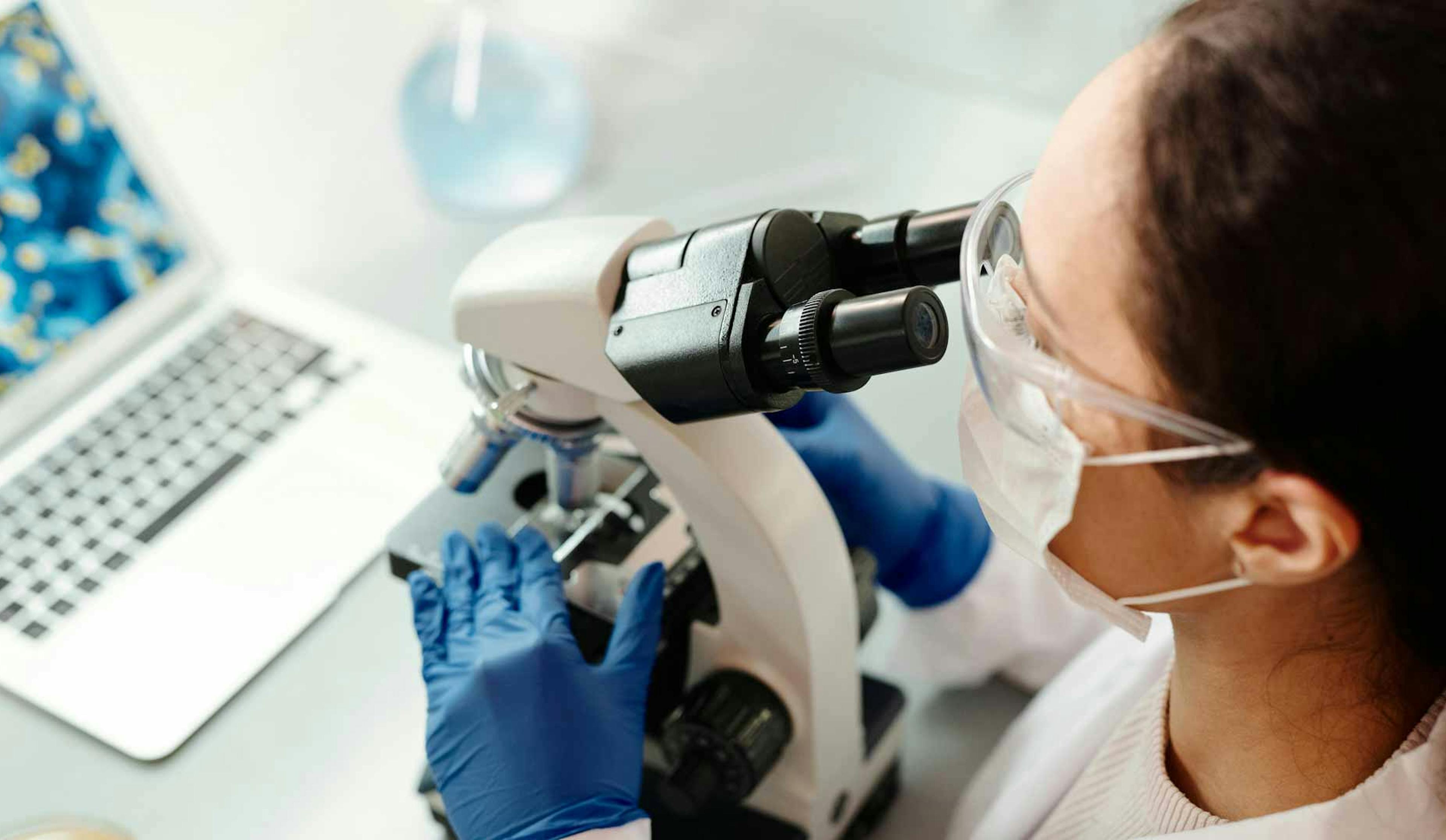 woman looking through microscope