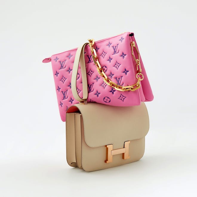 A luxury pink purse balancing on top of a tan purse