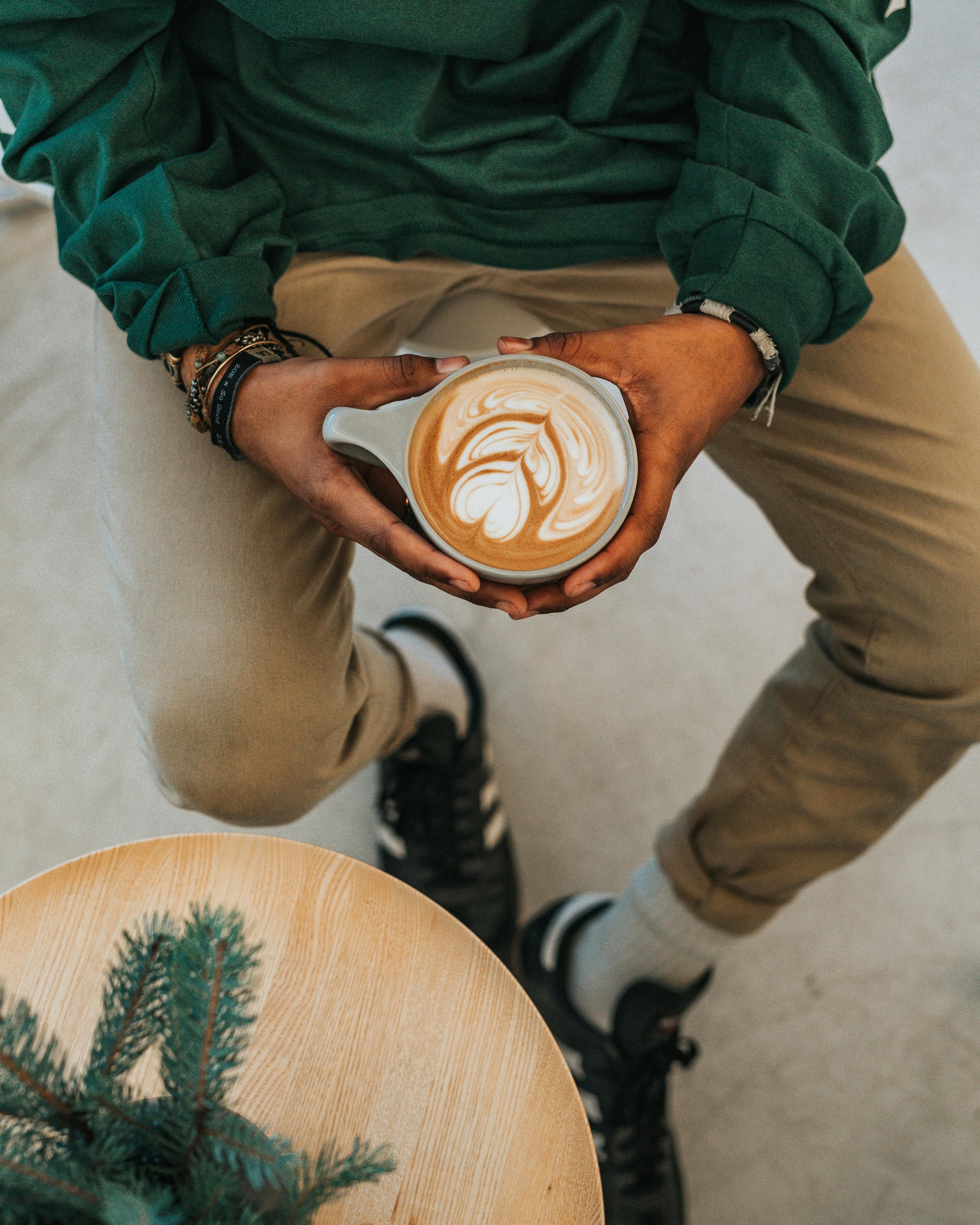 person sitting holding latte with design