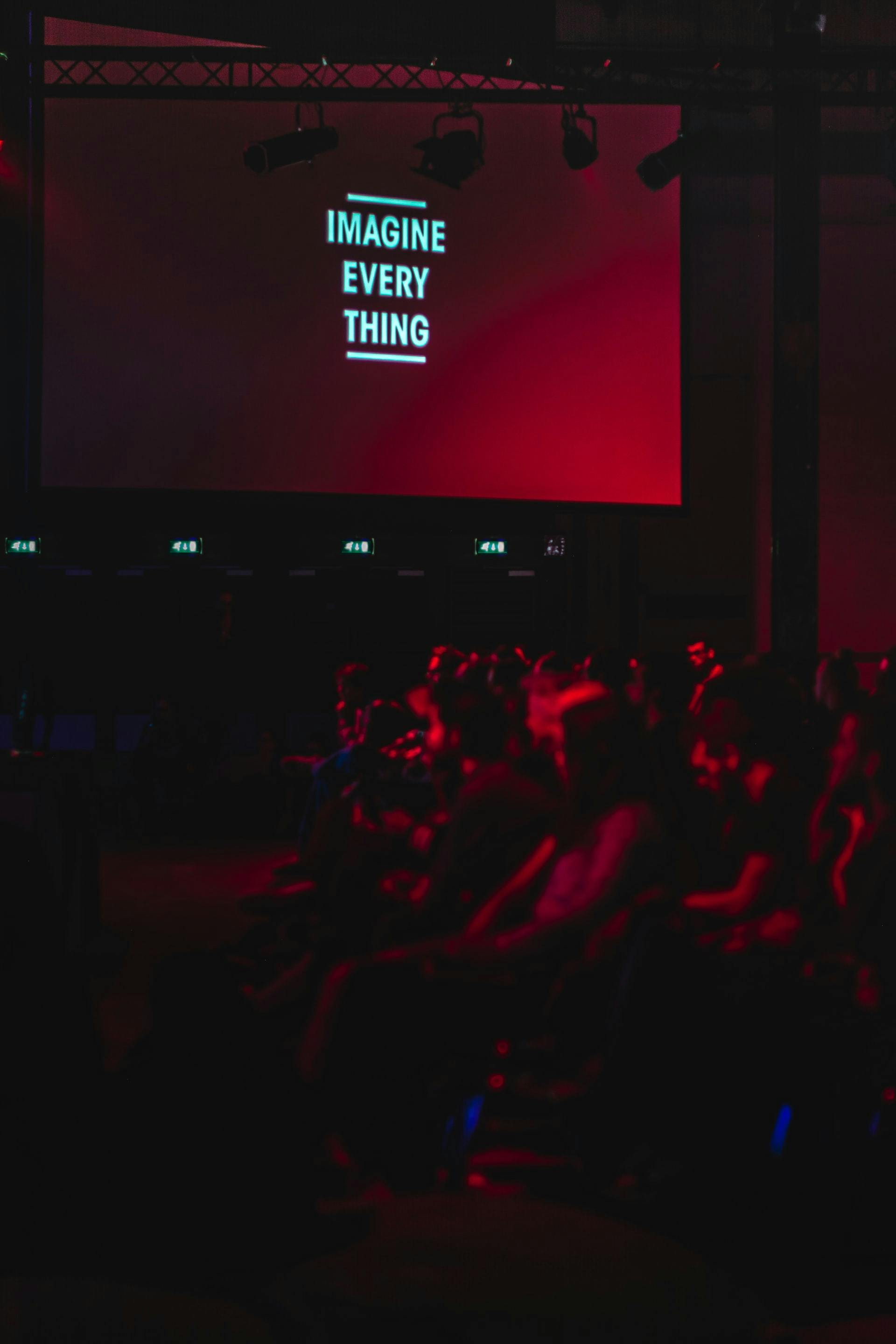audience looking at red screen with "imagine every thing" displayed.