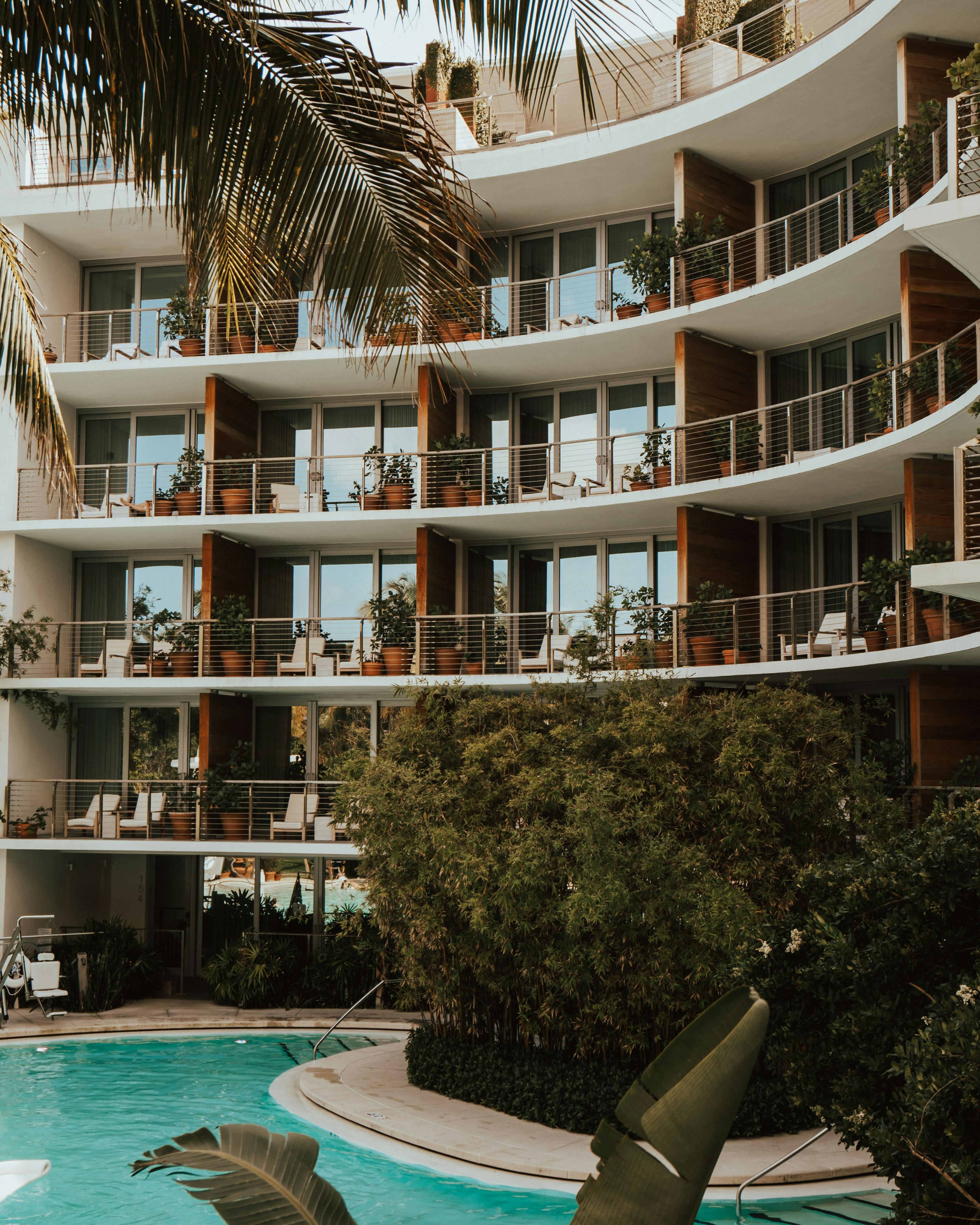 pool with a view of outdoor balconies and greenery at a hotel.