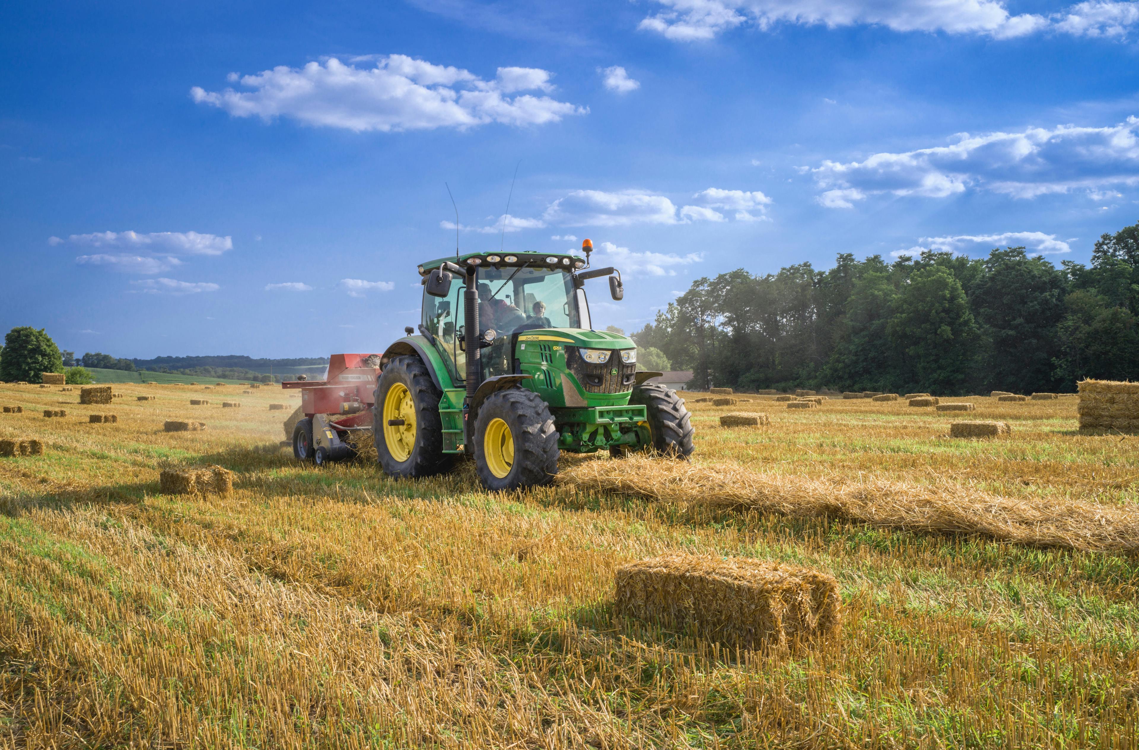 green tractor on brown grass field under blue sky during daytime.