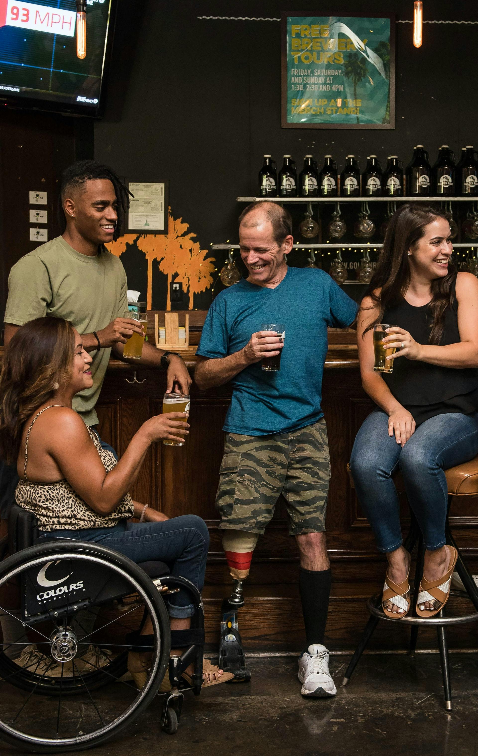 group of people holding drinks hanging out at a bar.