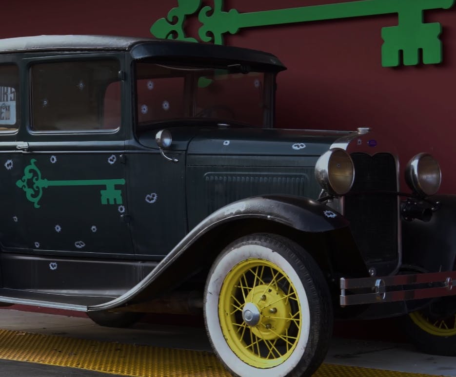 Image of the front door of the syndicate woodland hills classic car with bullet holes and syndicate key logo