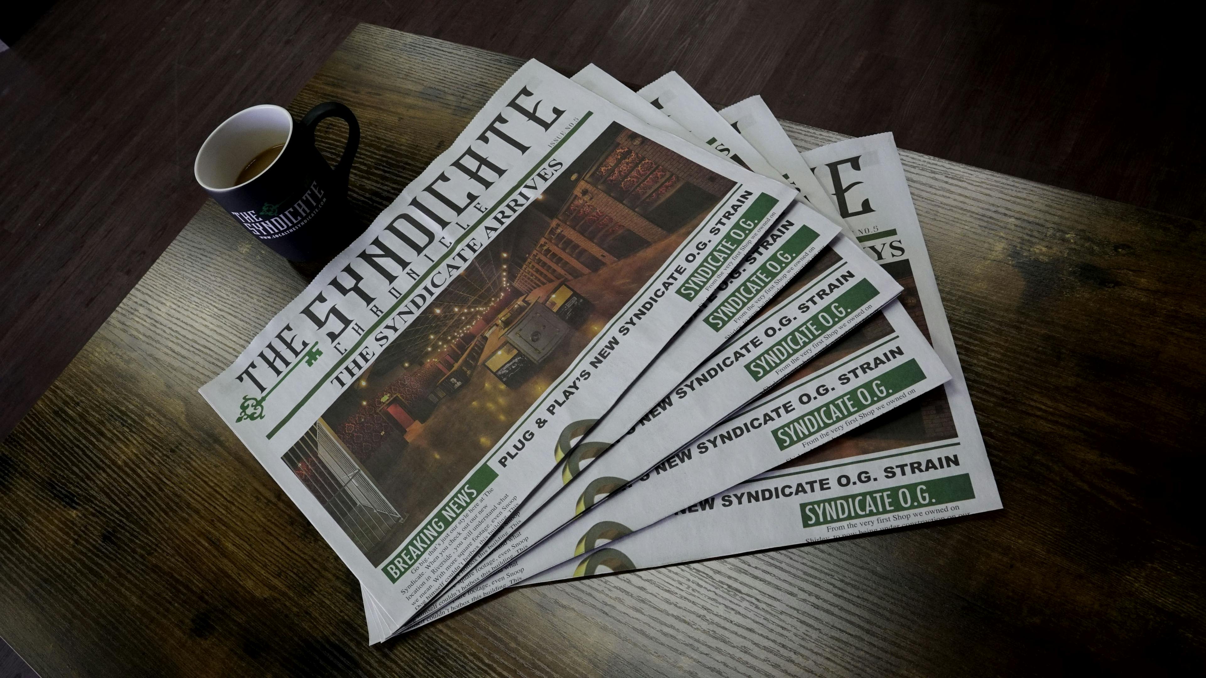 The Syndicate newspaper with a cup of coffee on a table