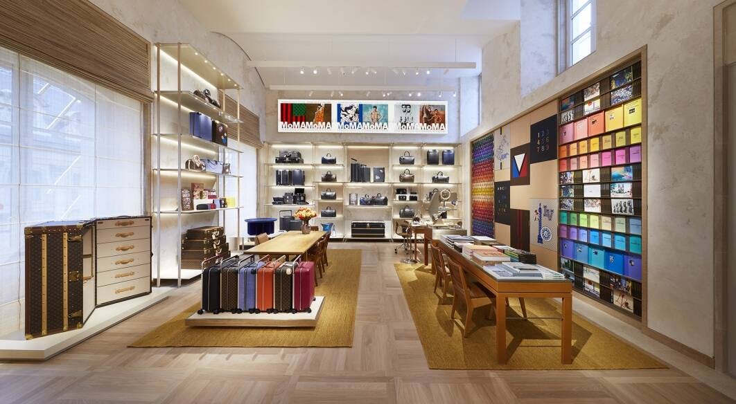 The interior of a Louis Vuitton brand store with tables, trunks, cases and artwork