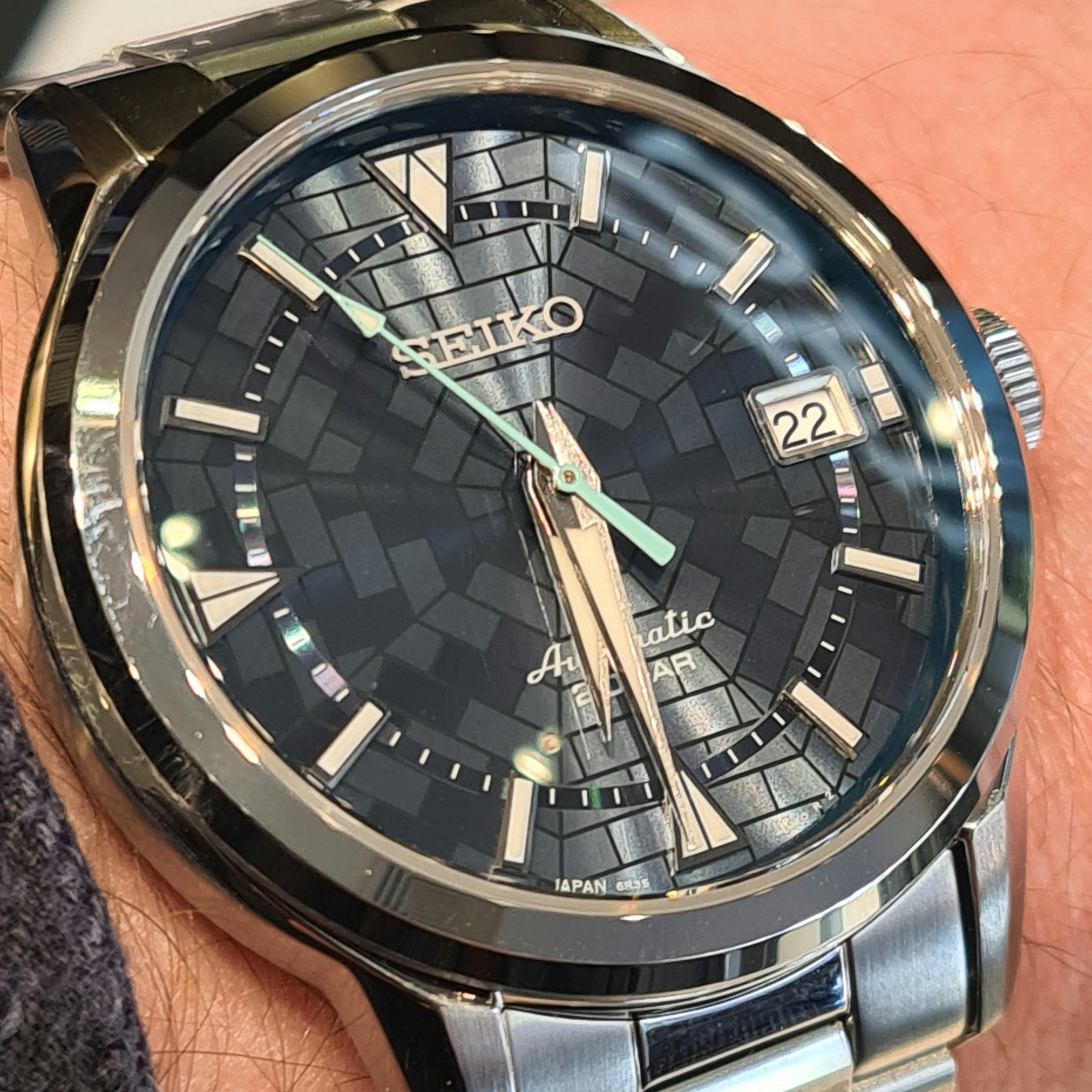 CLose up of a Seiko Alpinist watch with a special green-blue dial with luminous hands and a lightblue seconds hand. 