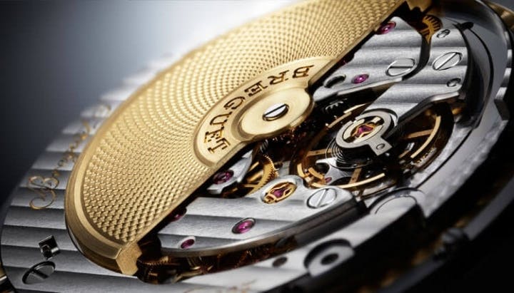 The gold rotor of this Breguet movement is decorated with guilloche. It contrasts beautifully with the Cotes de Geneve finishing on the rest of the movement