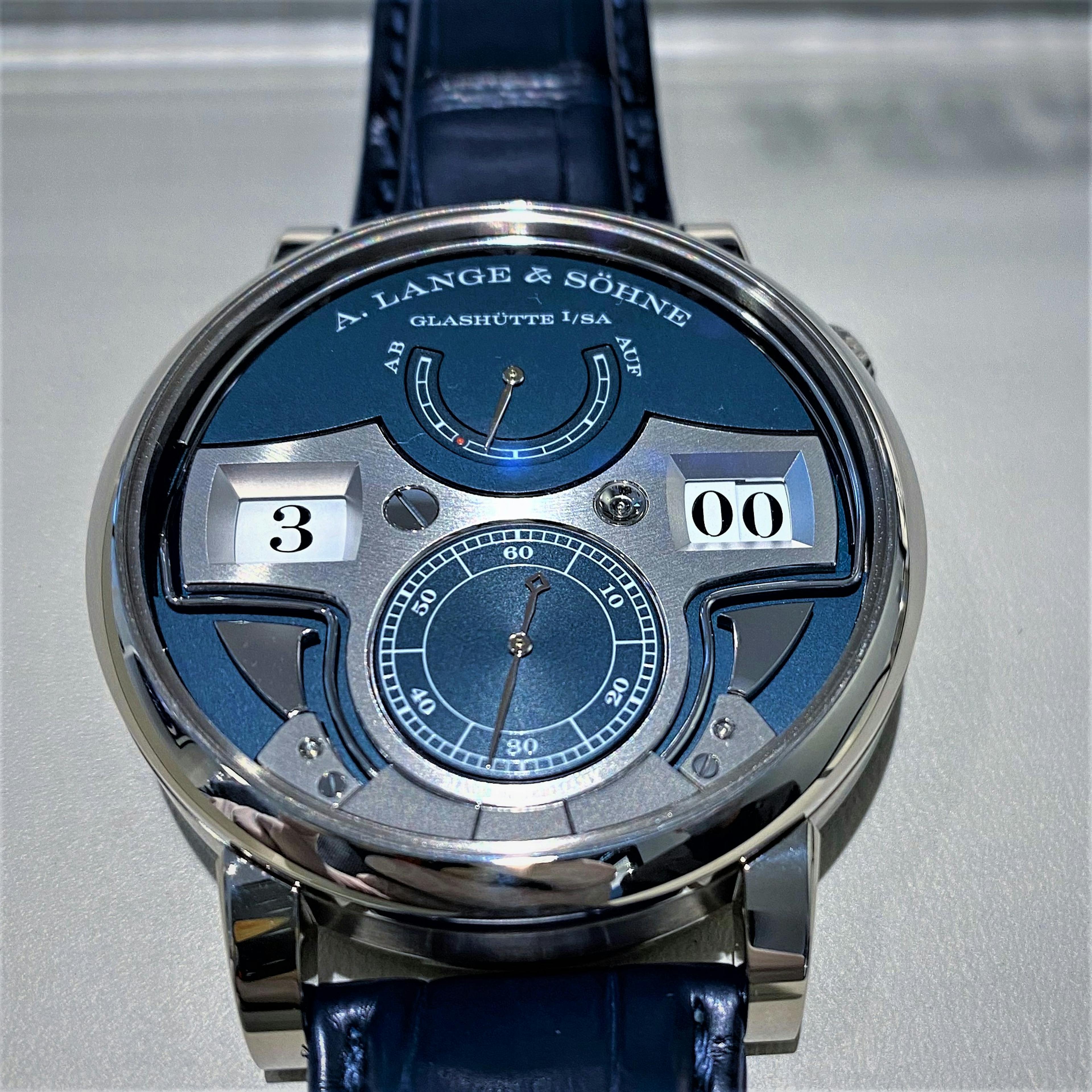 A Large white gold watch with blue dial with silver accents with large numbers showing the time ina d igital display with the small seconds on a dial at six 0'clock, with chiming gongs at the bottom and a power reserve at the top