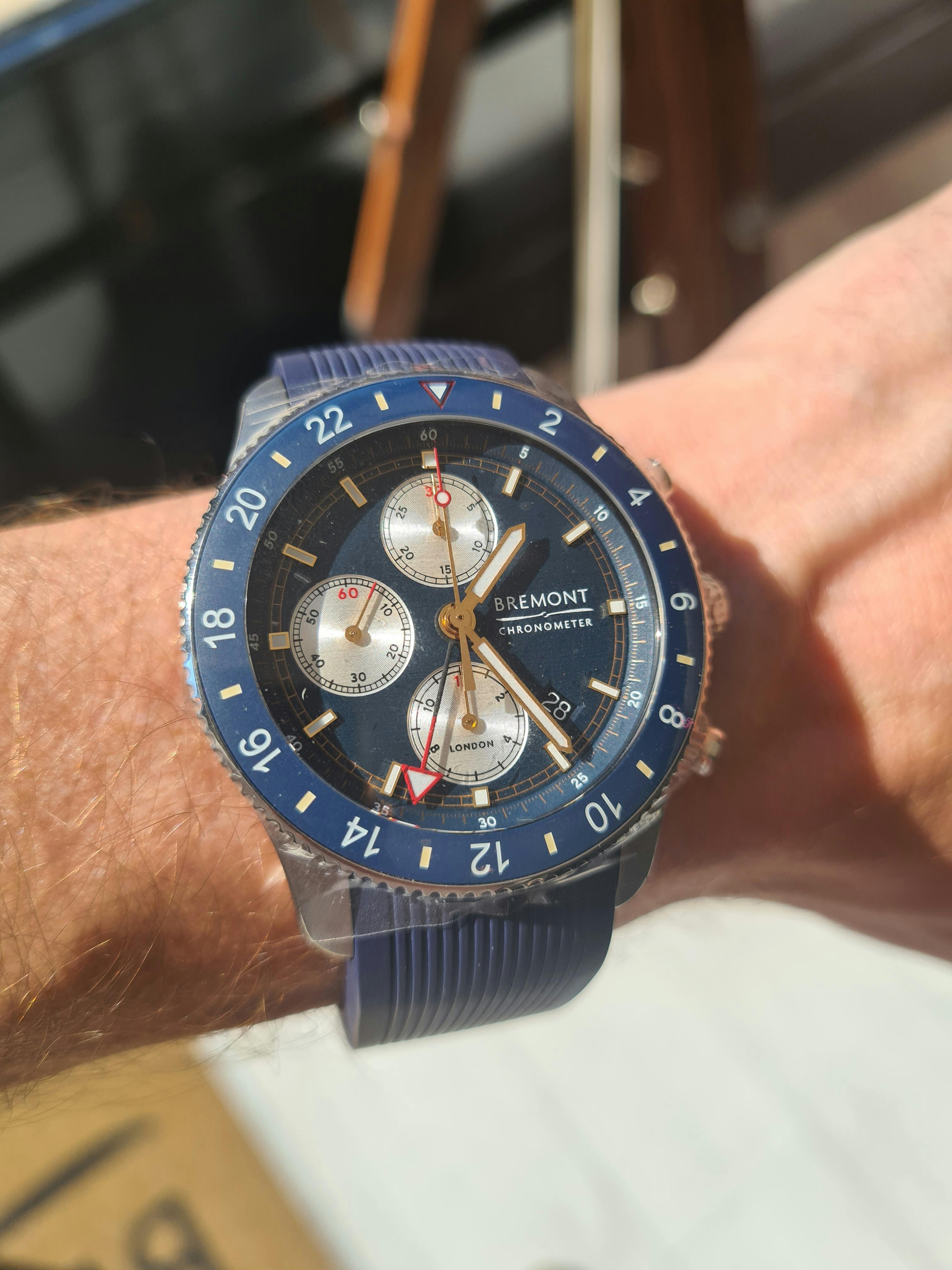 Large Blue dive watch with blue bezel and three silver subdials with red GMT hand and long thim lumed main hands, on a blue rubber strap.