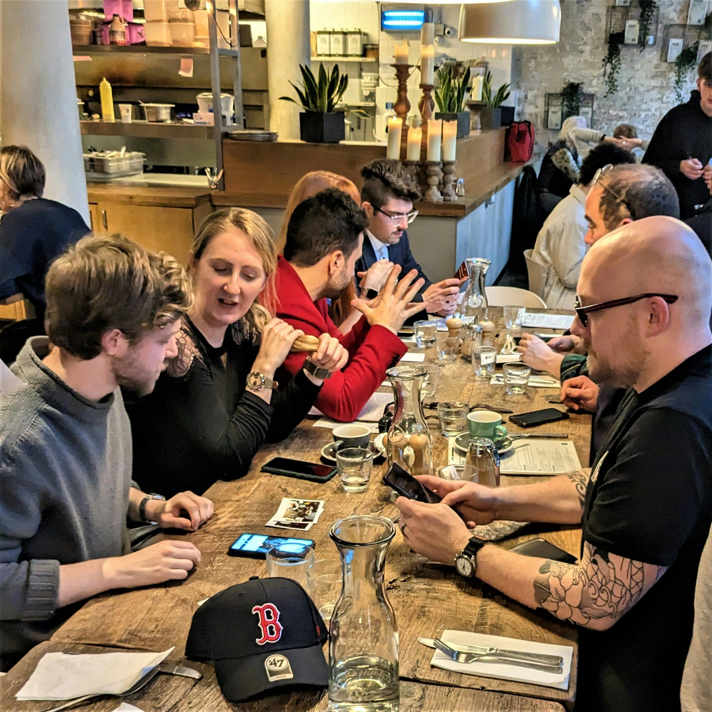 Watch collectors at a meetup over brunch sitting round a table talking and looking at watches