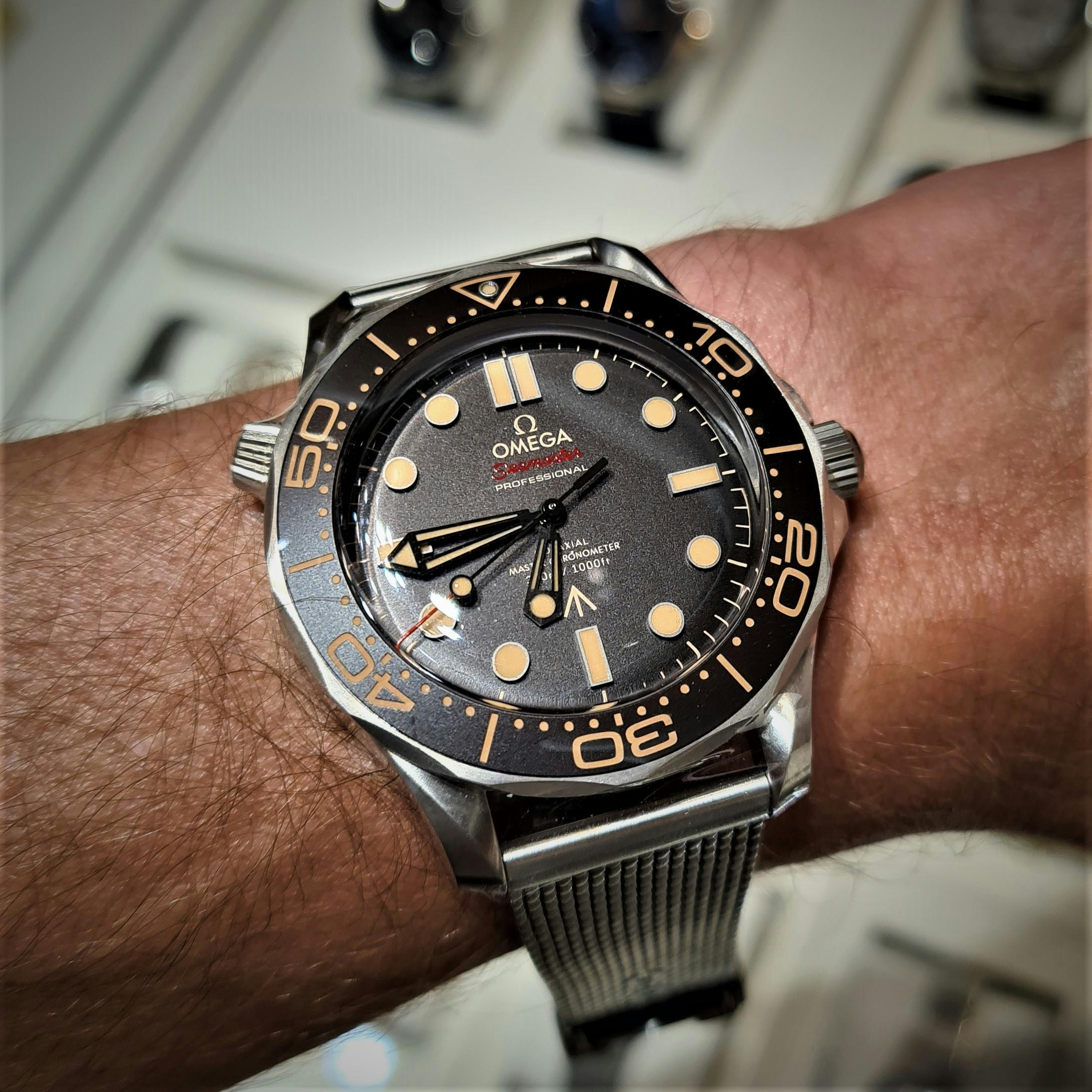 Large Omega wristwatch with black dial and bezel, faded yellow lume plots and see through hands with titanium case and strap