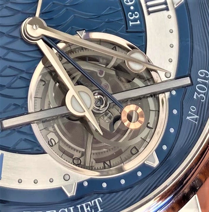 Close up of watch hands showing miniature sun and hours and minute hand above the Tourbillon mechanism