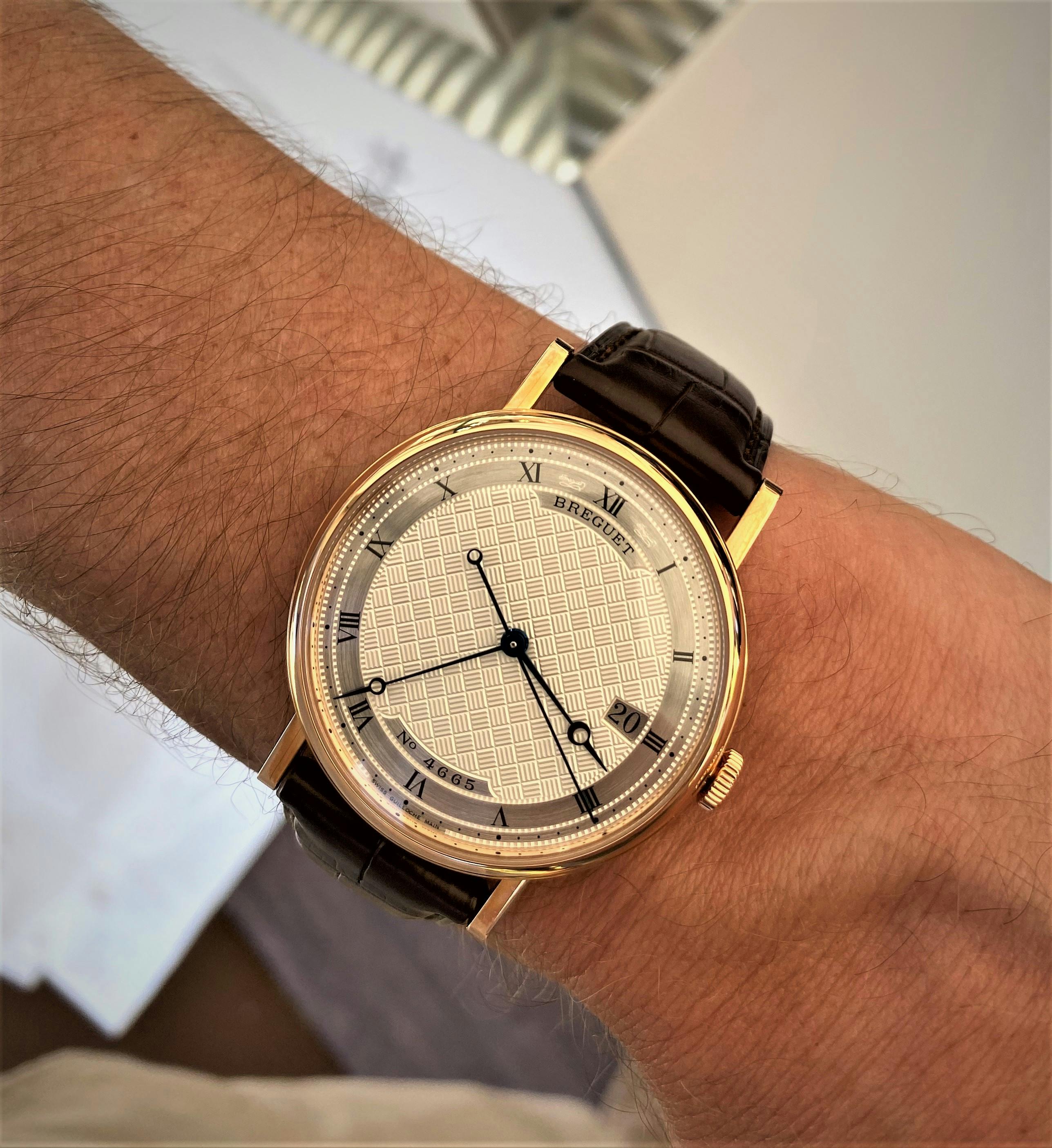 Bregeut Classique in gold case with white gold dial with dark blue hands on wrist 