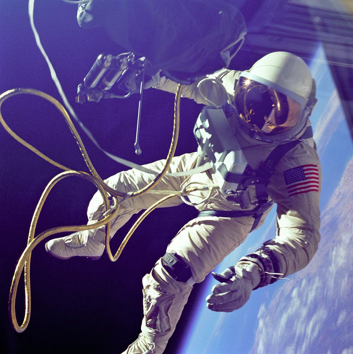 Astronaut floating in space with connecting air hoses with earth in background
