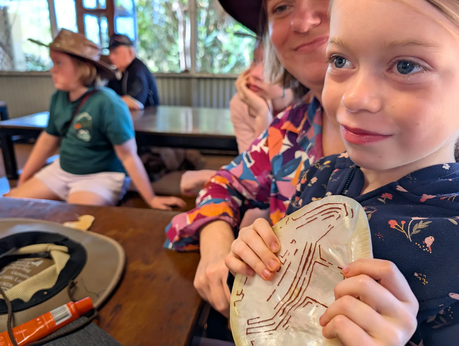 Josie holding an example of a pearl shell decorated in a traditional manner, called riji. These decorated shells were used by men and boys as part of their ceremonies and ceremonial dress.