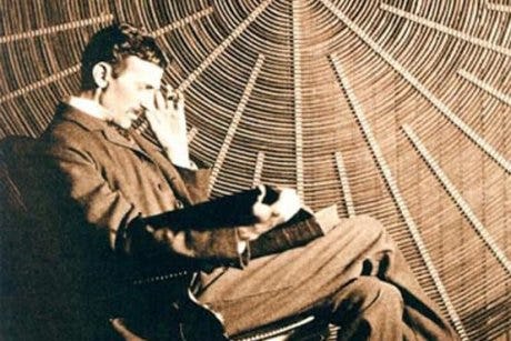Nikola Tesla in front of the spiral coil of his high frequency transformer in New York’ (credit: Wikimedia Commons)