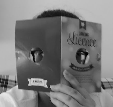 A black and white photo of the author peeking through holes in a birthday card congratulating the recipient on getting their driver's license. (Image credit to the Gunaydin family, particularly B., S. and M. Gunaydin, as well as A. Marinho, Dorine Setakwe and Kristen Ordonio.)