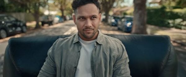 A photo of a man on a leather armchair outside on a street.