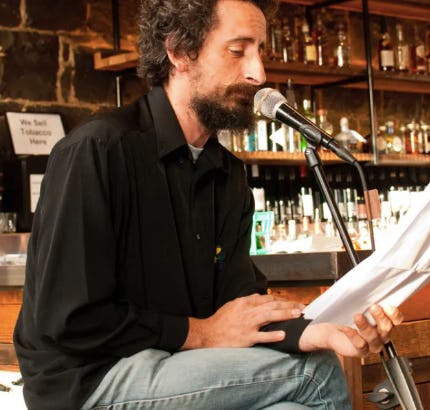 photo of Eyal Chipkiewicz doing a reading at a microphone 