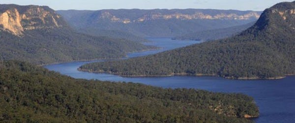 A photo of a landscape: blue river and green trees