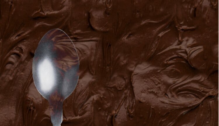 An image of a spoon against a background of chocolate frosting