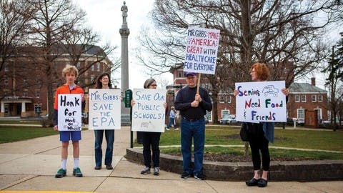 Protesters demonstrate in the Mount Vernon town square, holding signs calling for the protection of public schools, the Environmental Protection Agency, Meals on Wheels, and health care.