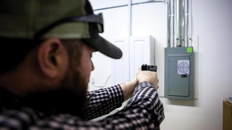 Chris Jones aims his pistol at a bullseye on the wall