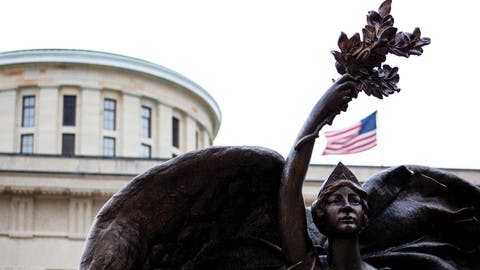 A statue of a woman lifting an olive branch above her head