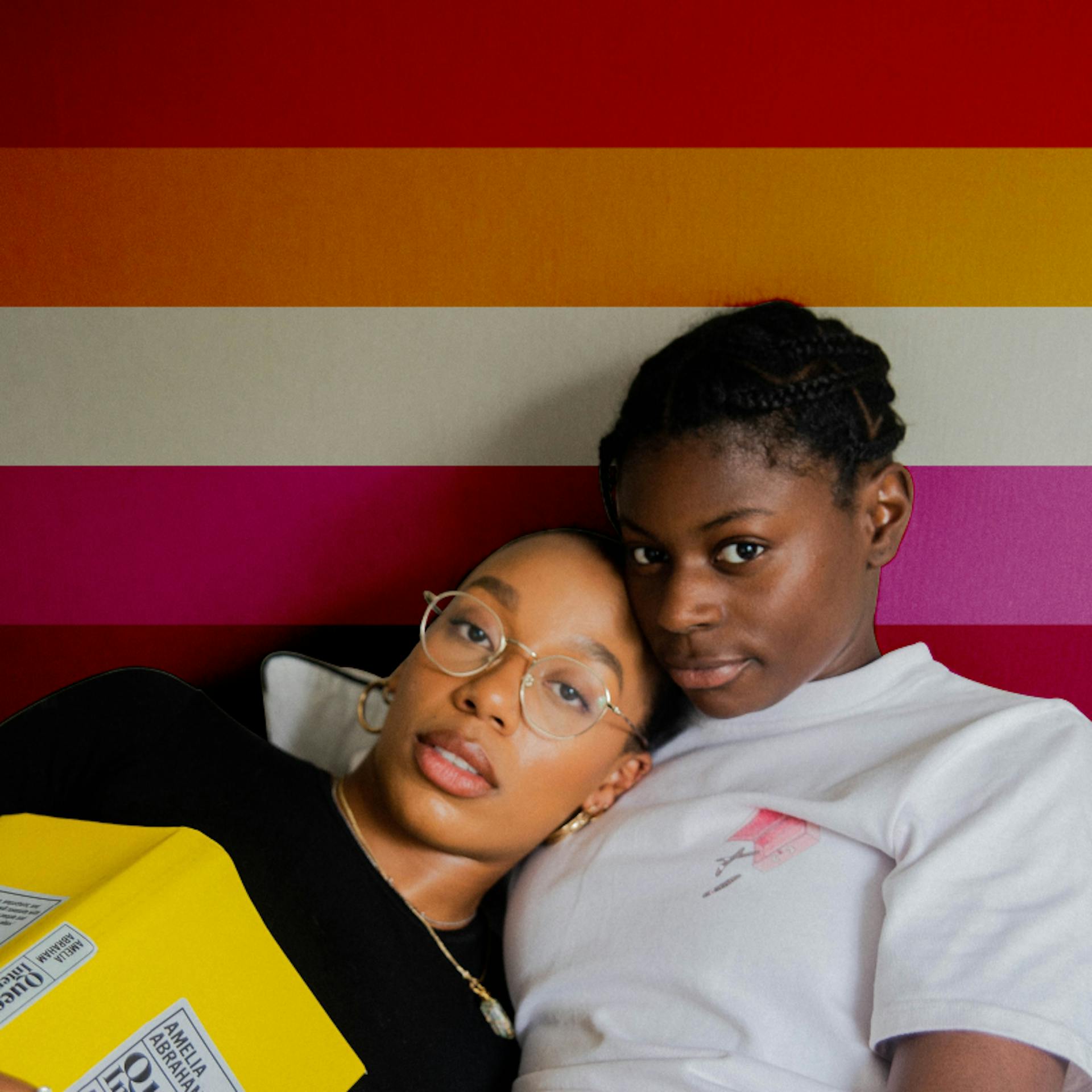 A lesbian couple in front of the lesbian pride flag.