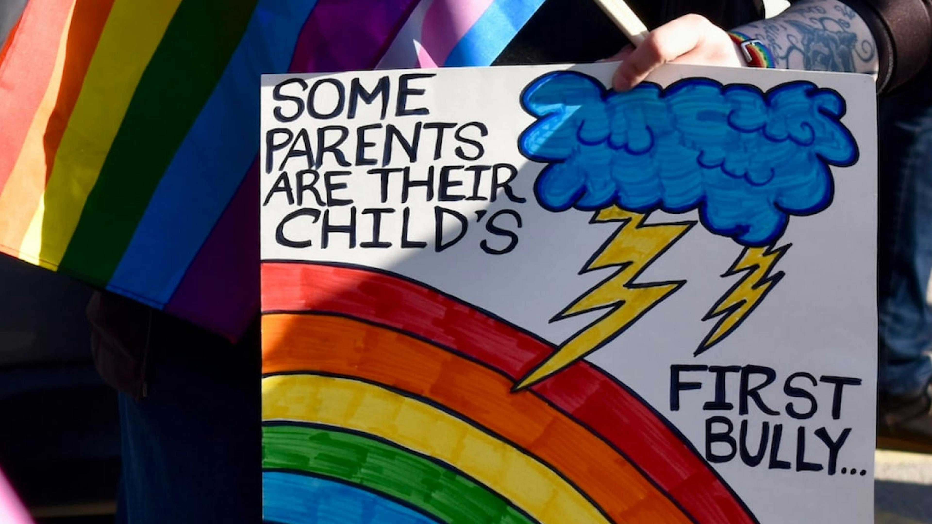 A sign with a rainbow reading "some parents are their child's first bully."