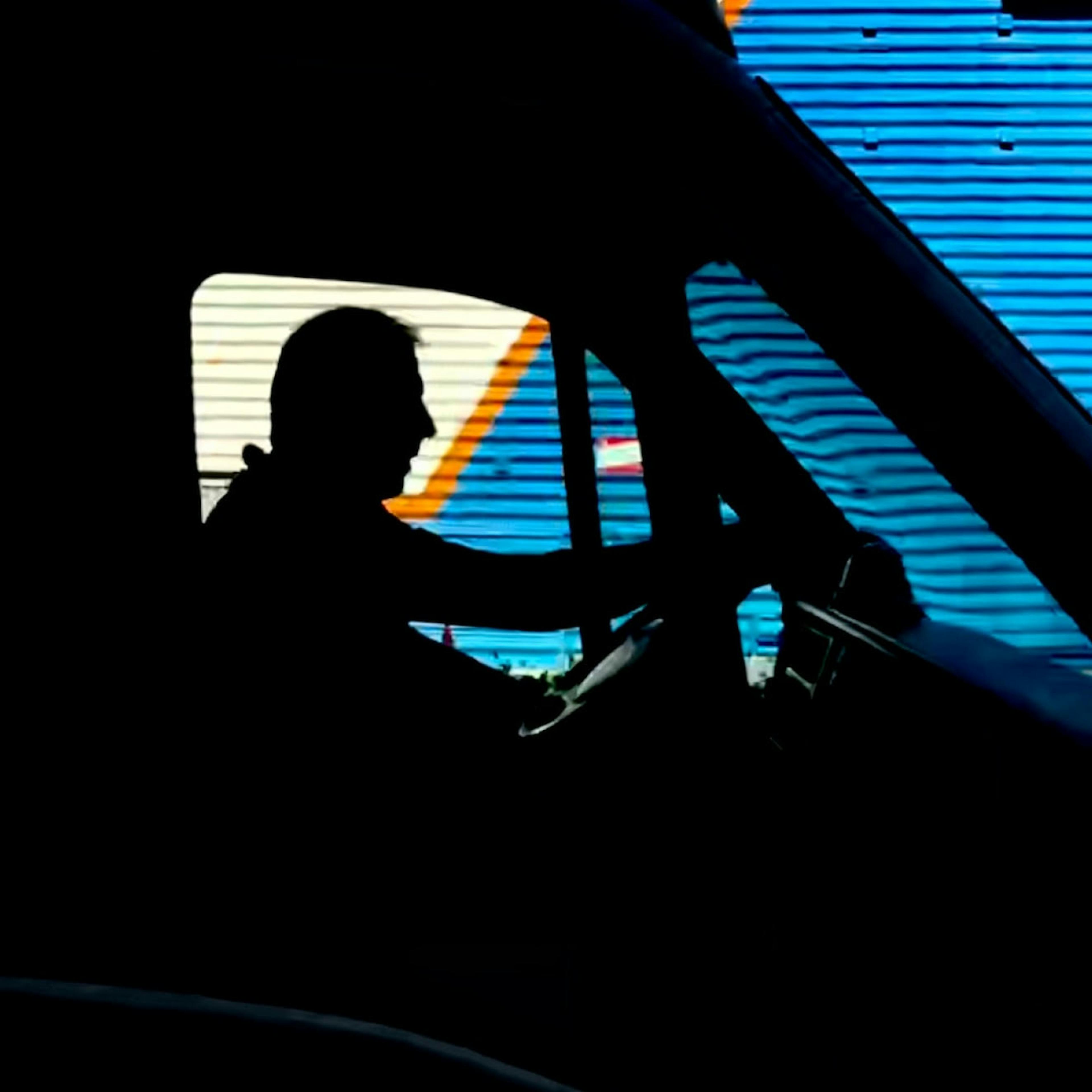 A silhouette of a truck driver behind the wheel.
