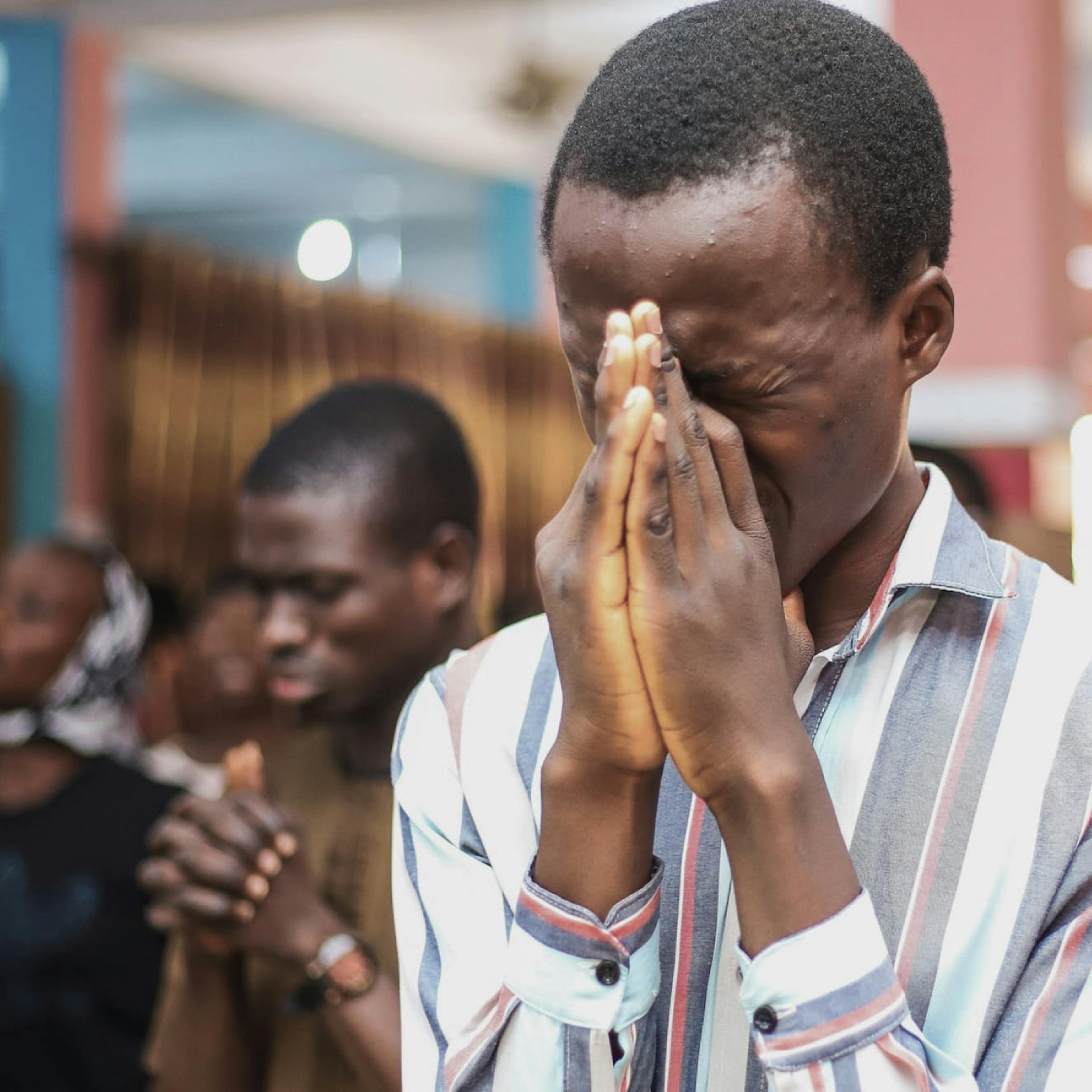 Nigerian men praying fervently at church.