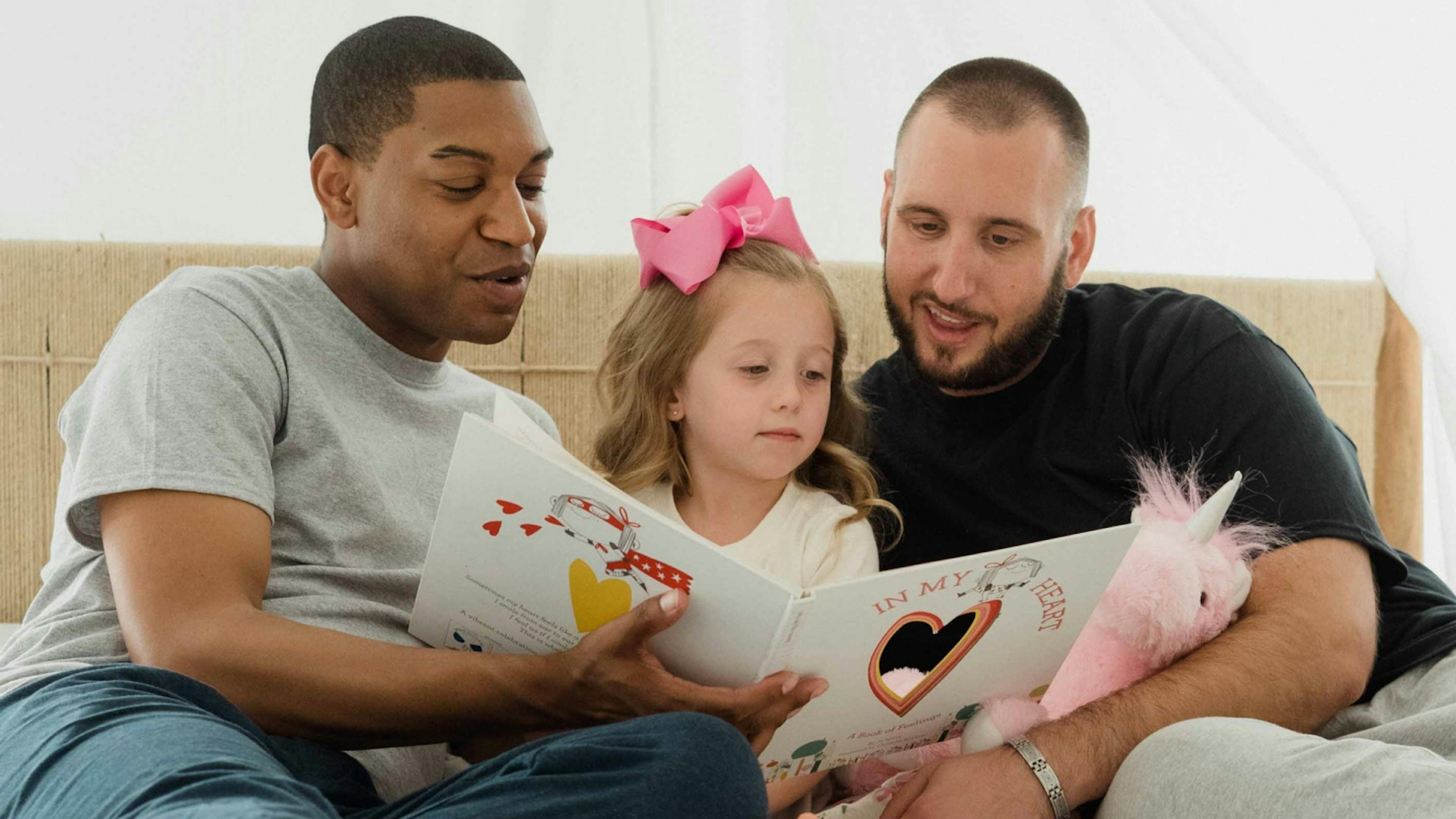 A gay couple reads to their niece in preparation of having their own children some day.