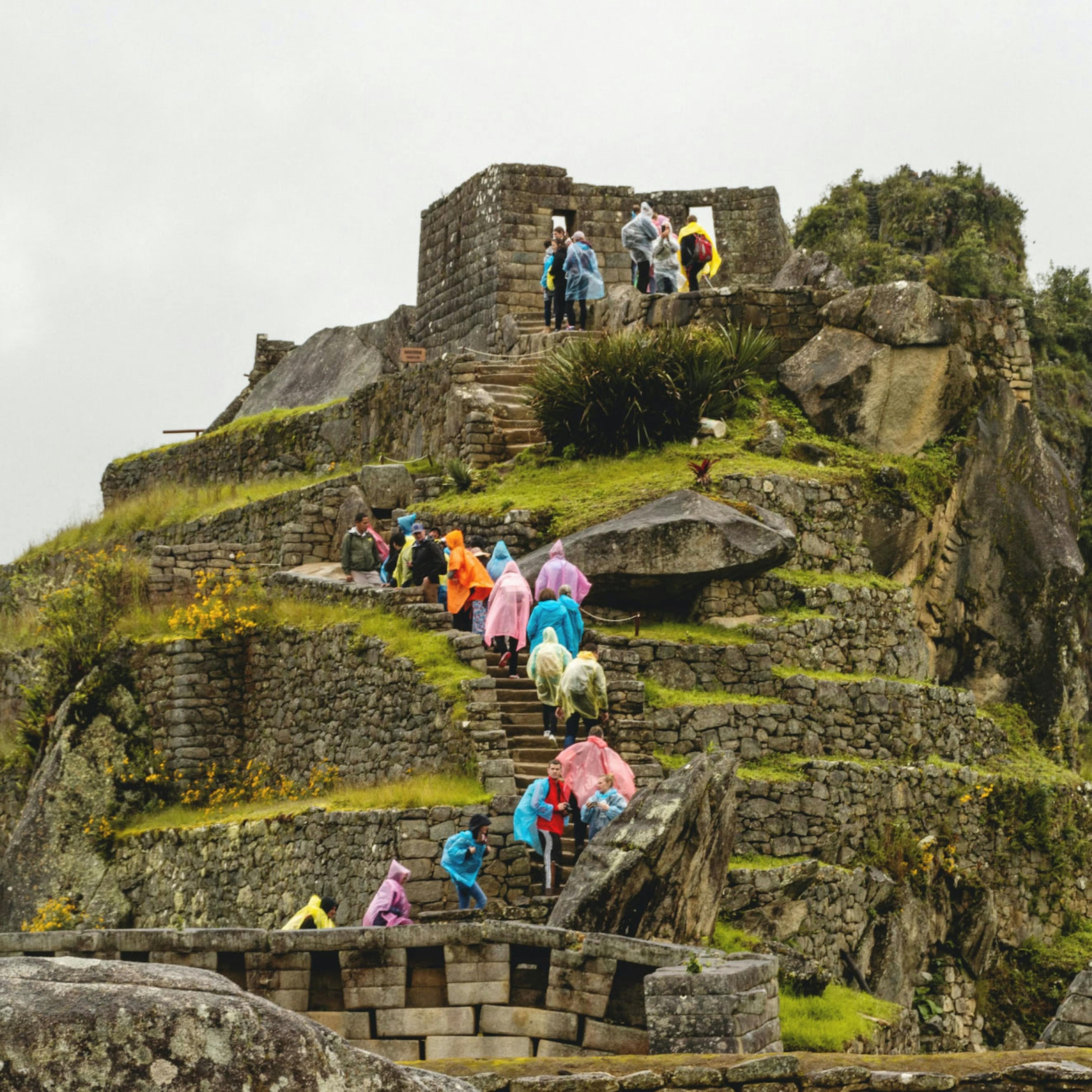 Tourists and ex-pats climbing the structures at Machu Picchu in Cusco, Peru.