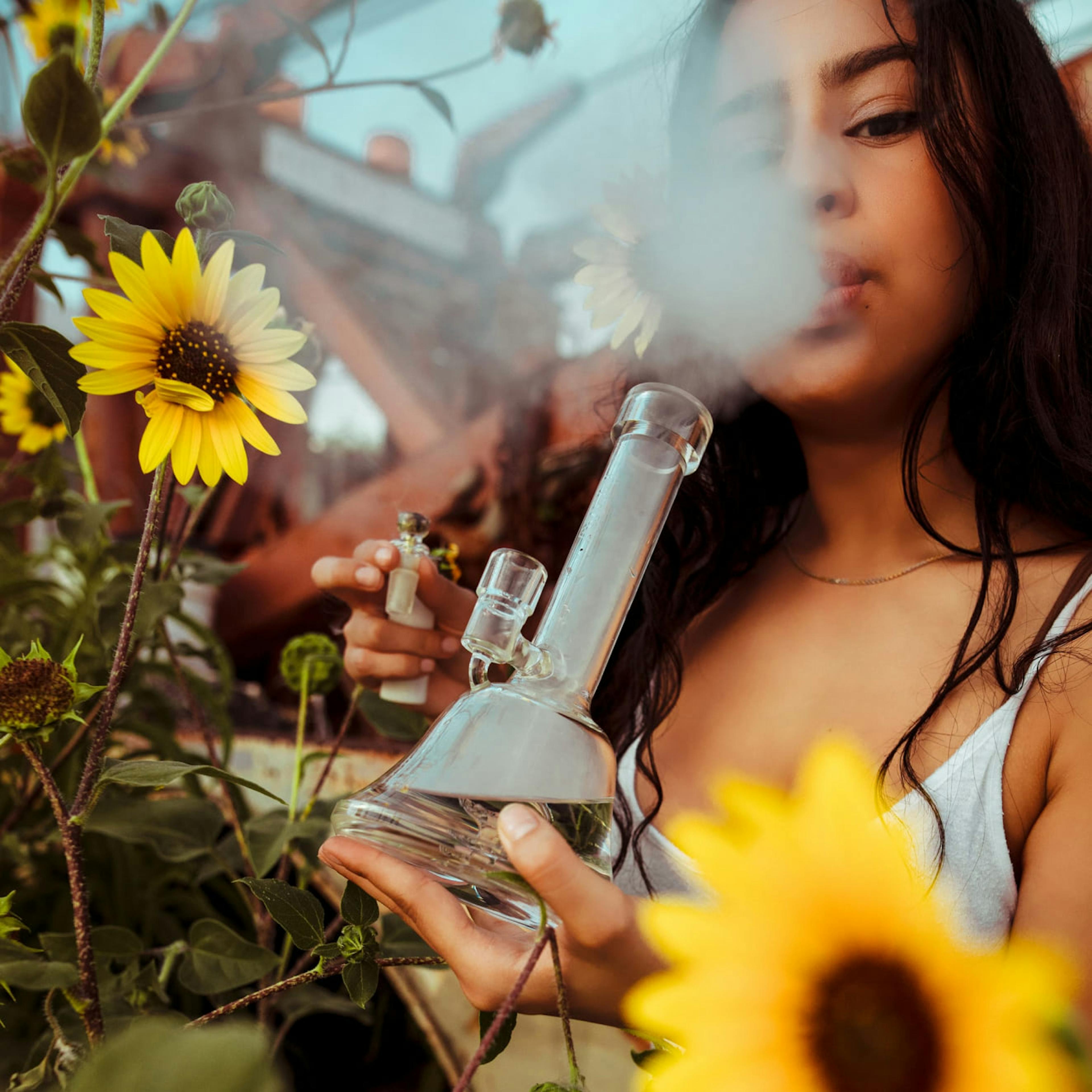A young woman smokes weed from a bong in the California desert.