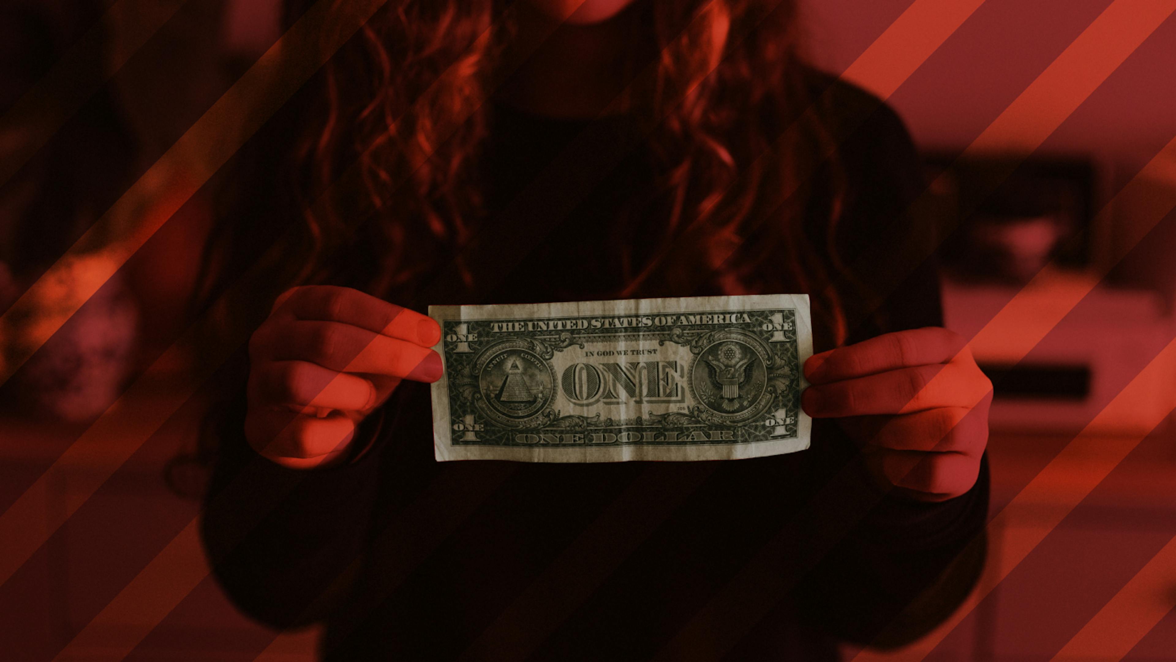 An exploited child worker holding a one dollar bill.