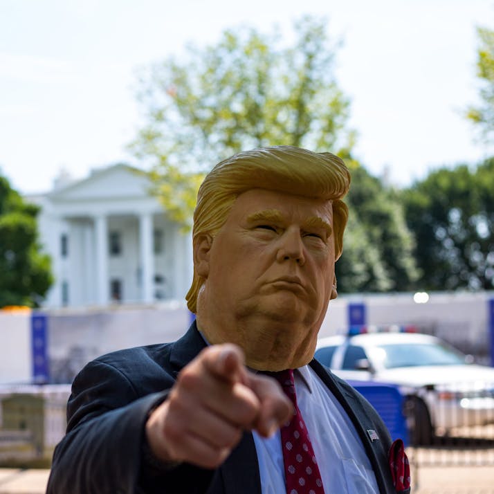 A man wears a Donald Trump mask