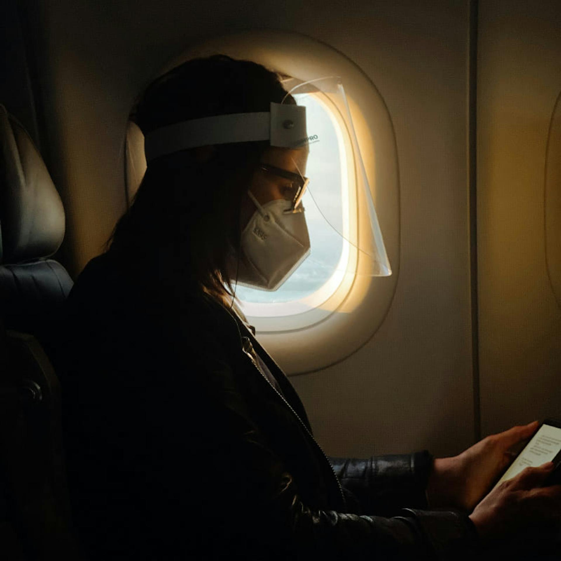 A passenger following the FAA rules by wearing a face mask and shield during their flight.