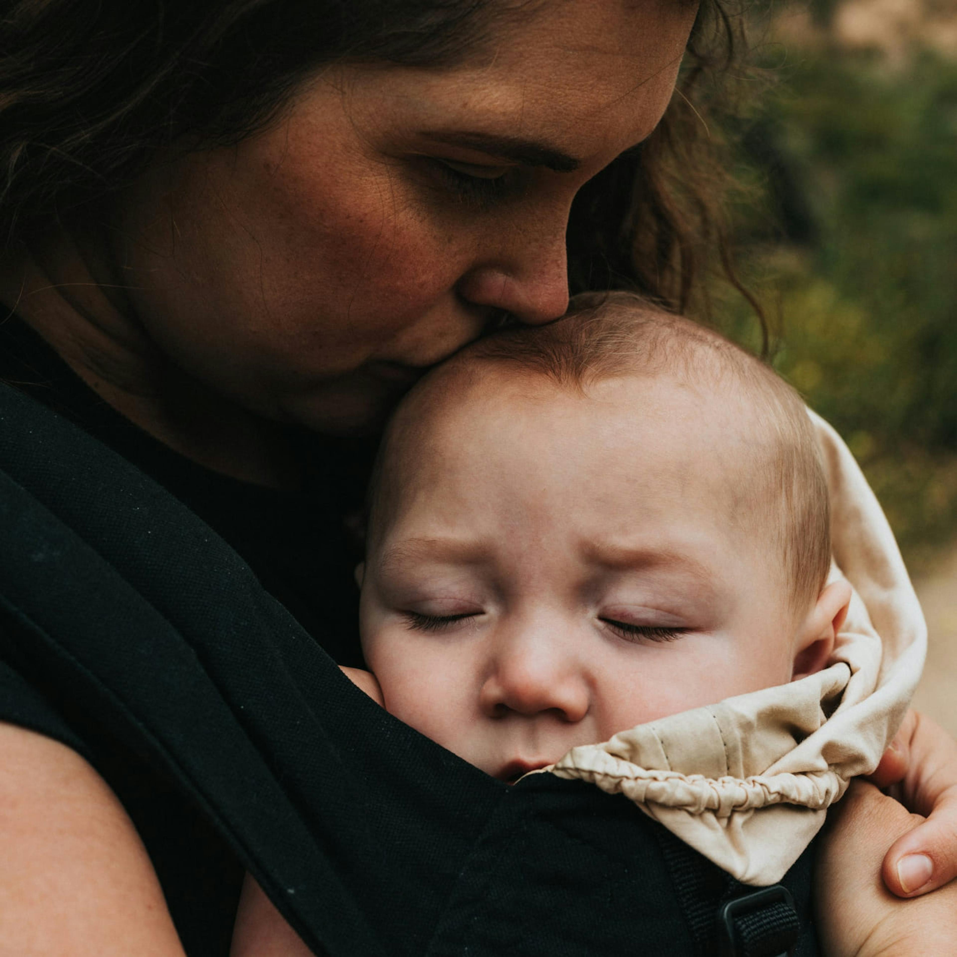 A mother tenderly kissing her baby's head.